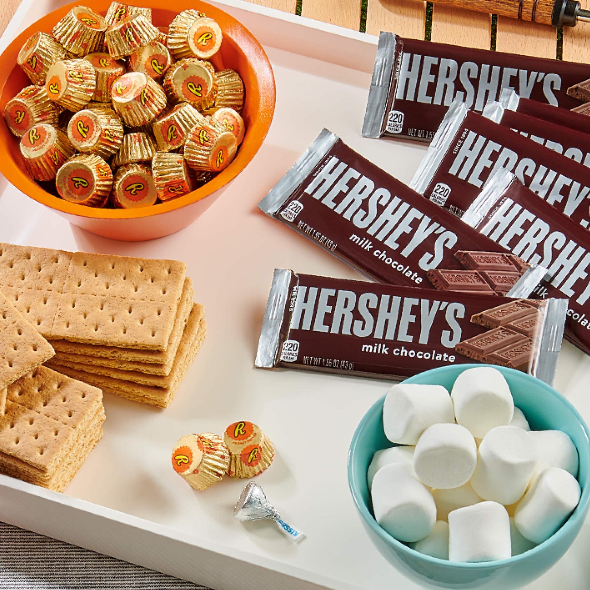 tray topped with graham crackers, marshmallows, reeses peanut butter cups, and hersheys milk chocolate bars