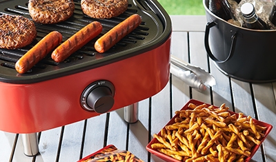 grill with hotdogs and hamburgers next to bowl of dots pretzels