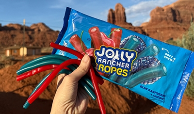 bag of jolly rancher ropes being held in front of dessert rocks